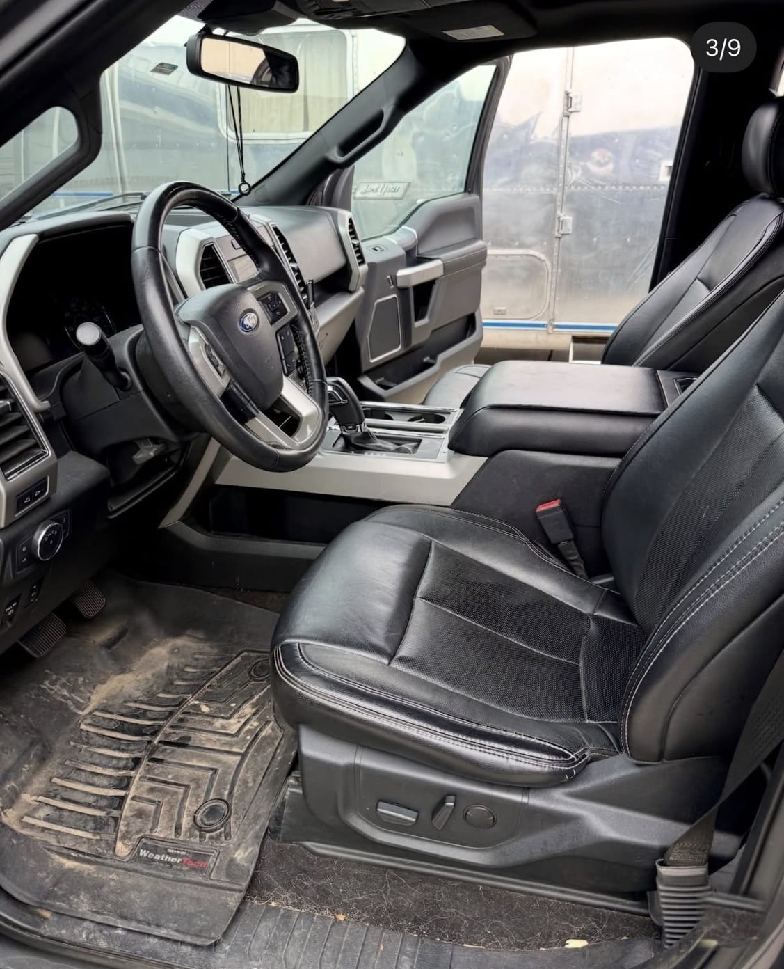 Ford pickup truck interior with dusty, mud-caked floor mats and a dirty floorboard, before detailing.